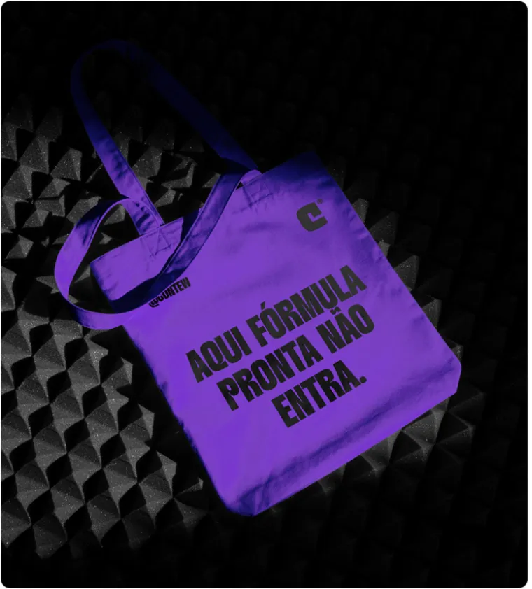 Ecobag roxa com a frase 'Aqui fórmula pronta não entra' em letras pretas, sobre uma superfície preta